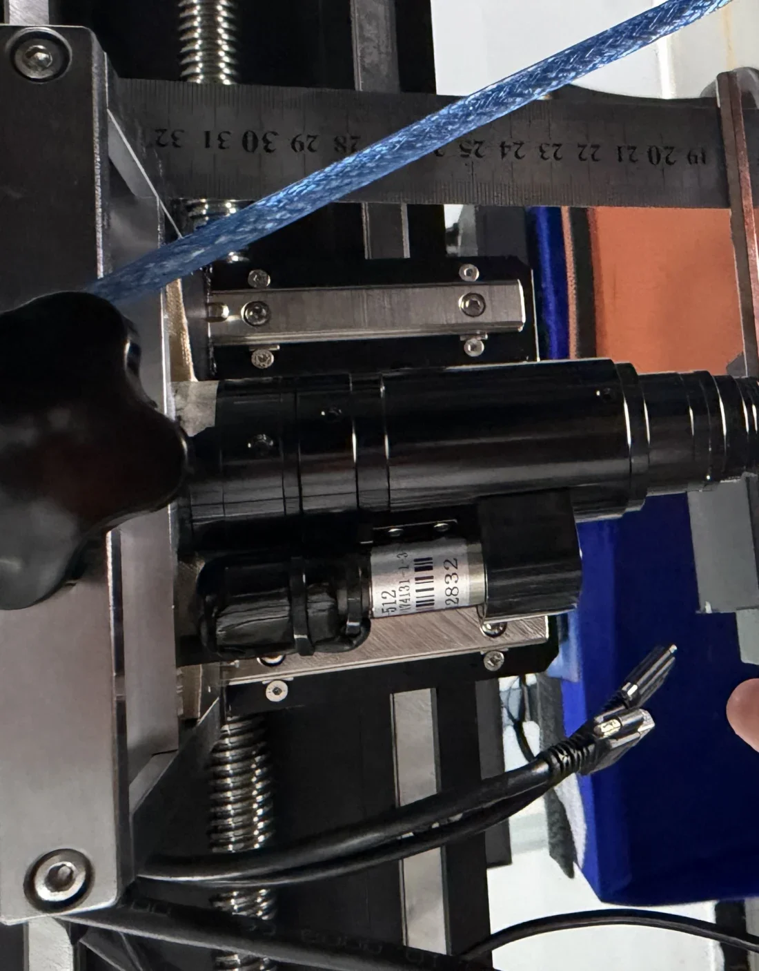 Gros plan du bloc moteur latéral et de la monture C de l'objectif zoom motorisé : servomoteur, câble et connecteur